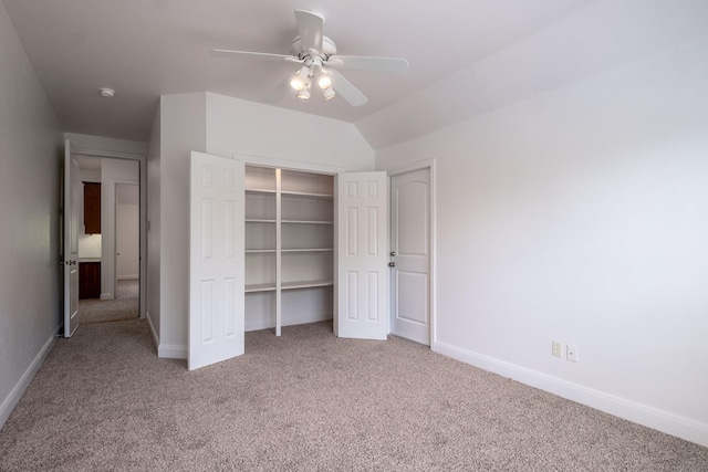 unfurnished bedroom featuring ceiling fan, vaulted ceiling, a closet, and carpet flooring