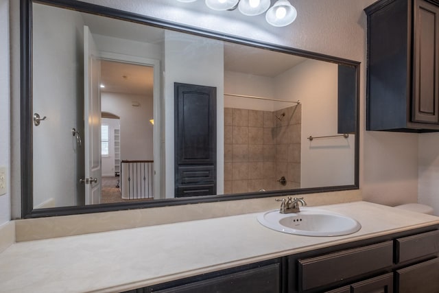 bathroom featuring a tile shower and vanity