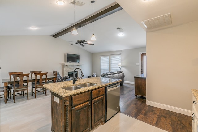 kitchen with vaulted ceiling with beams, ceiling fan, stainless steel dishwasher, a brick fireplace, and sink