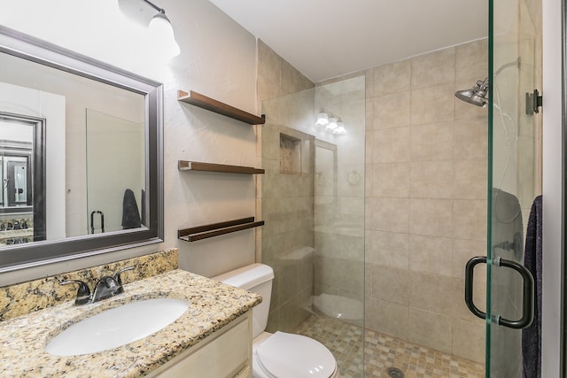 bathroom with toilet, vanity, and a shower with shower door