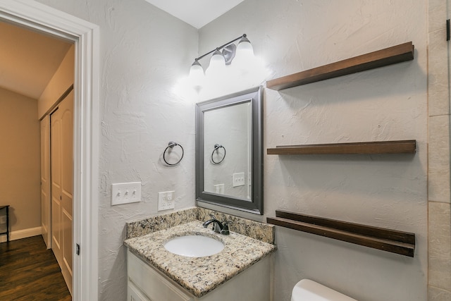 bathroom with hardwood / wood-style flooring, toilet, and vanity