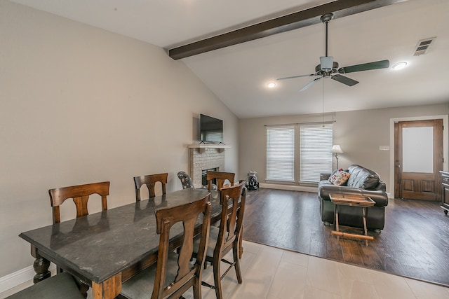 dining space with ceiling fan, vaulted ceiling with beams, light wood-type flooring, and a fireplace