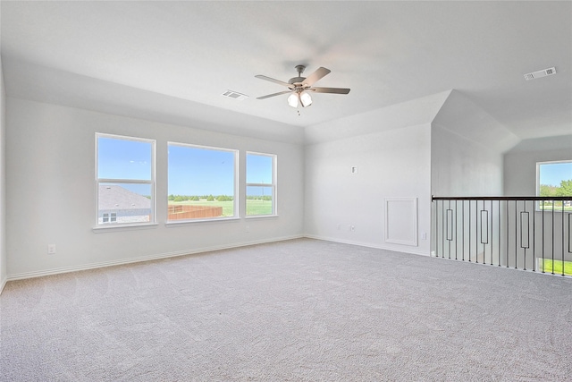 carpeted empty room with ceiling fan, plenty of natural light, and lofted ceiling