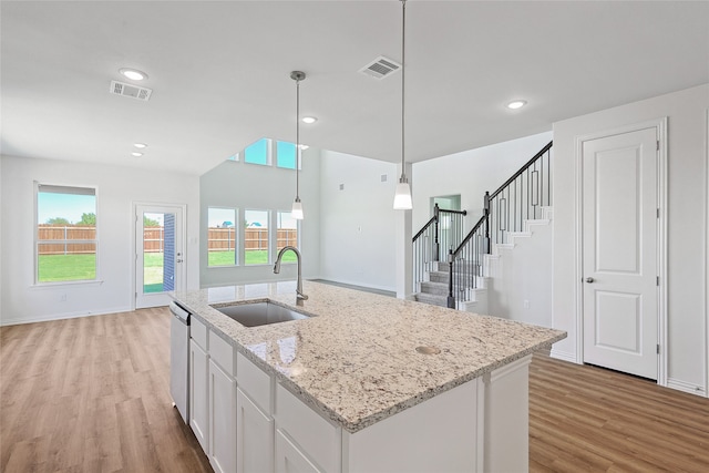 kitchen featuring white cabinetry, dishwasher, light wood-type flooring, decorative light fixtures, and sink