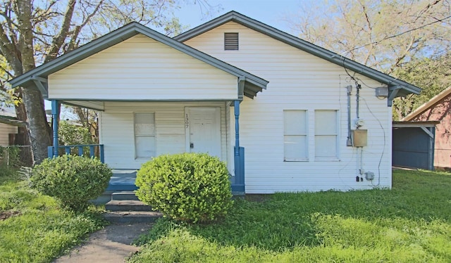 bungalow-style home featuring covered porch and a front yard