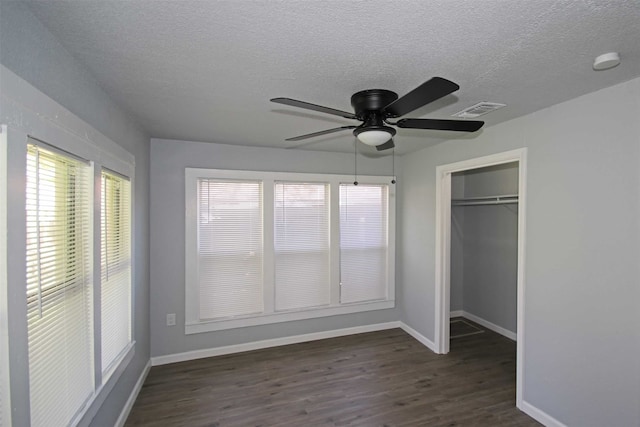 unfurnished bedroom with dark hardwood / wood-style flooring, a textured ceiling, ceiling fan, and a closet