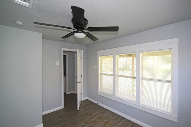 empty room with dark wood-type flooring, a textured ceiling, and ceiling fan