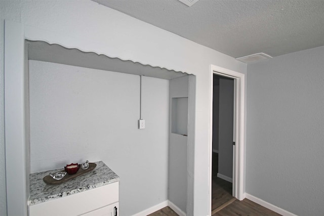 interior space with white cabinetry, dark hardwood / wood-style floors, and a textured ceiling