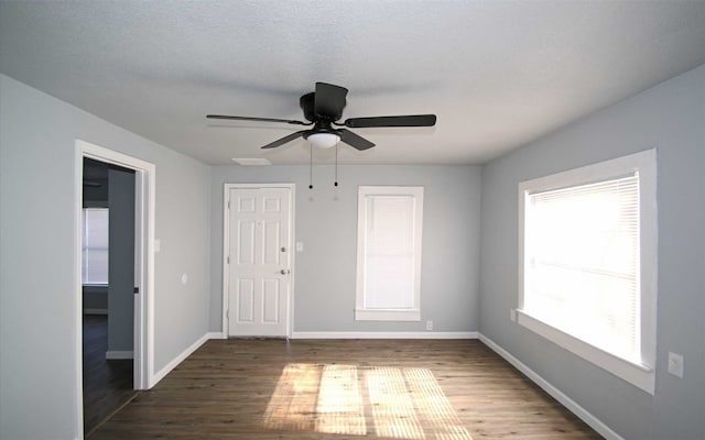 unfurnished room featuring dark wood-type flooring, ceiling fan, plenty of natural light, and a textured ceiling