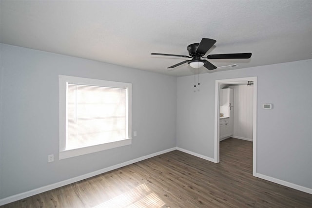 empty room with dark wood-type flooring, ceiling fan, and a textured ceiling