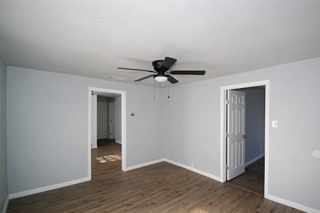 empty room featuring a textured ceiling, dark hardwood / wood-style flooring, and ceiling fan