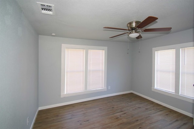 unfurnished room featuring ceiling fan, dark hardwood / wood-style floors, and a healthy amount of sunlight