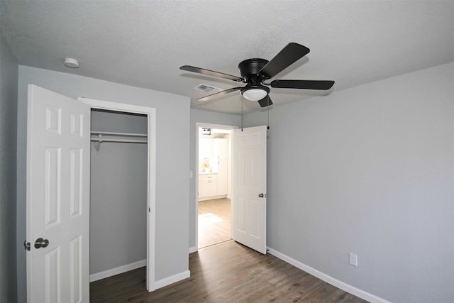 unfurnished bedroom featuring dark wood-type flooring, a textured ceiling, ceiling fan, and a closet