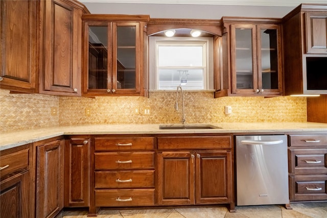 kitchen with sink, backsplash, stainless steel dishwasher, and light stone countertops