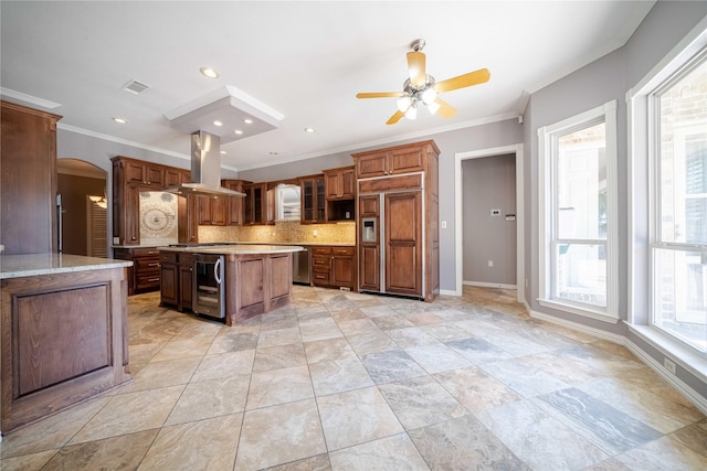 kitchen featuring a kitchen island, island exhaust hood, stainless steel appliances, beverage cooler, and backsplash