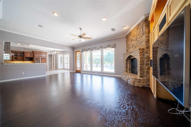 unfurnished living room featuring dark hardwood / wood-style floors, ceiling fan, a stone fireplace, and crown molding