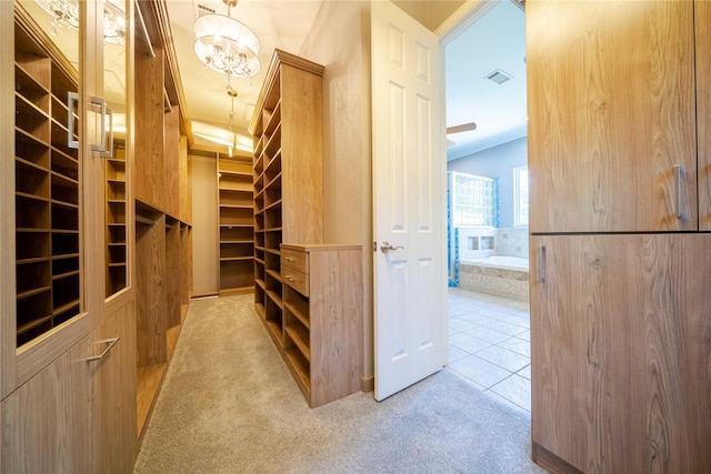 walk in closet featuring light colored carpet and a chandelier