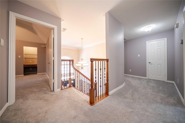 corridor featuring vaulted ceiling, carpet, crown molding, and an inviting chandelier