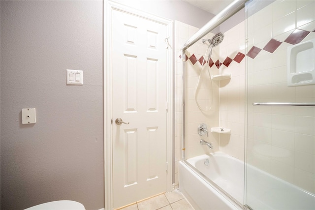 bathroom with bath / shower combo with glass door and tile patterned floors