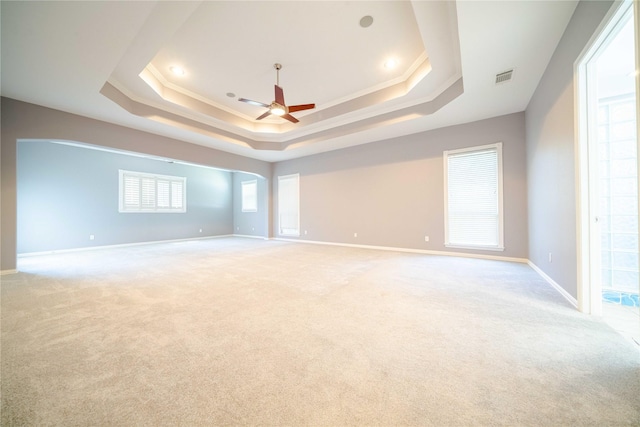 empty room with crown molding, ceiling fan, and a raised ceiling