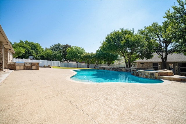 view of pool with an in ground hot tub, an outdoor kitchen, and a patio area