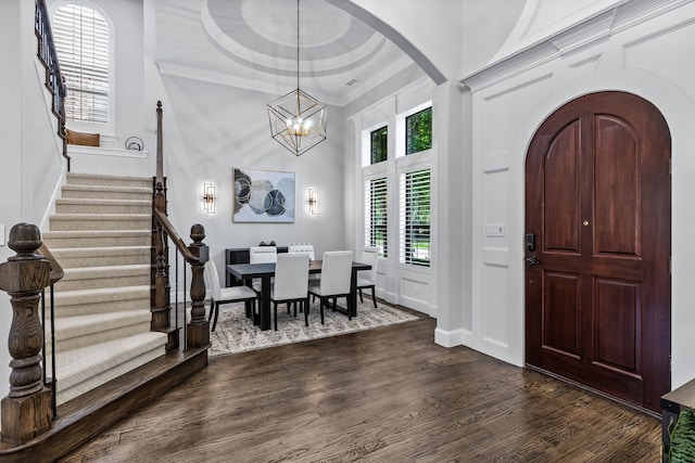 entryway with a high ceiling, crown molding, dark hardwood / wood-style floors, and a chandelier