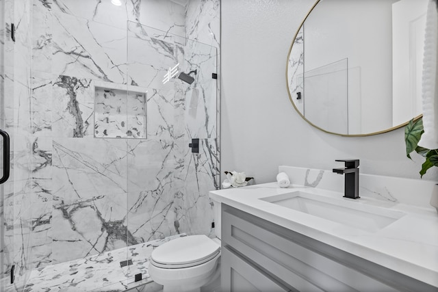 bathroom featuring vanity, a shower with shower door, and toilet