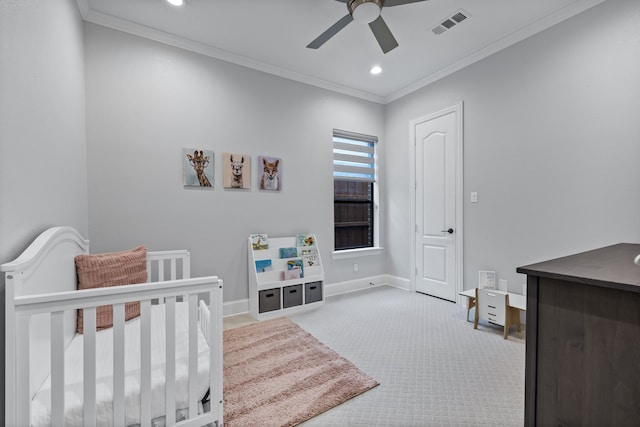 carpeted bedroom with ornamental molding, a crib, and ceiling fan