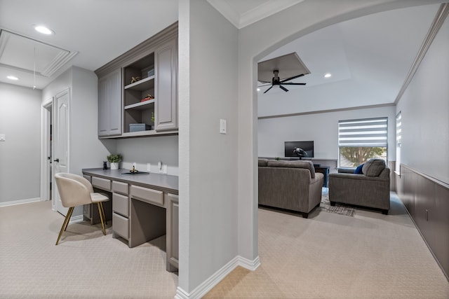 carpeted office with built in desk, crown molding, and ceiling fan