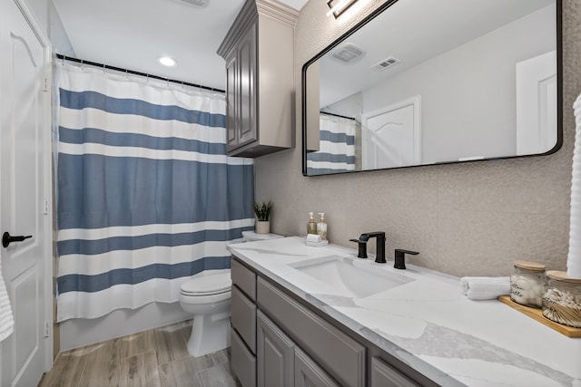 bathroom featuring vanity, toilet, hardwood / wood-style flooring, and decorative backsplash