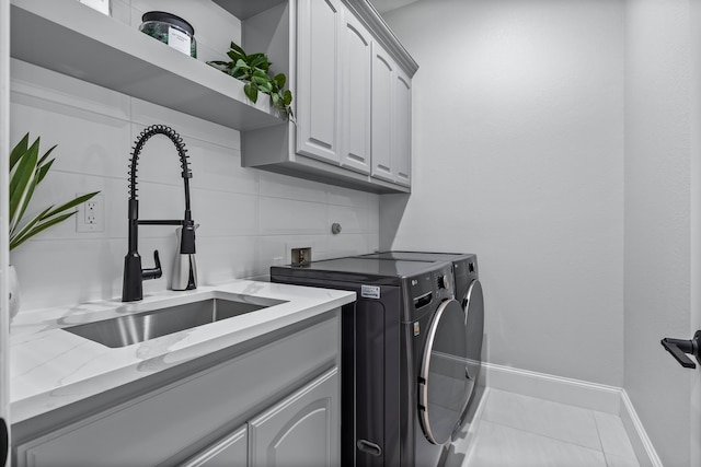 clothes washing area with cabinets, independent washer and dryer, sink, and light tile patterned floors