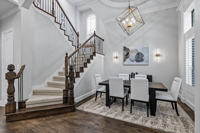 dining area with an inviting chandelier, crown molding, hardwood / wood-style flooring, and a towering ceiling