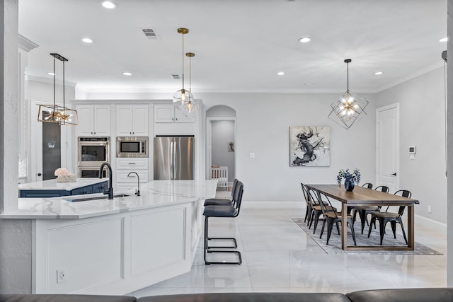 kitchen with stainless steel appliances, sink, light stone countertops, decorative light fixtures, and white cabinets