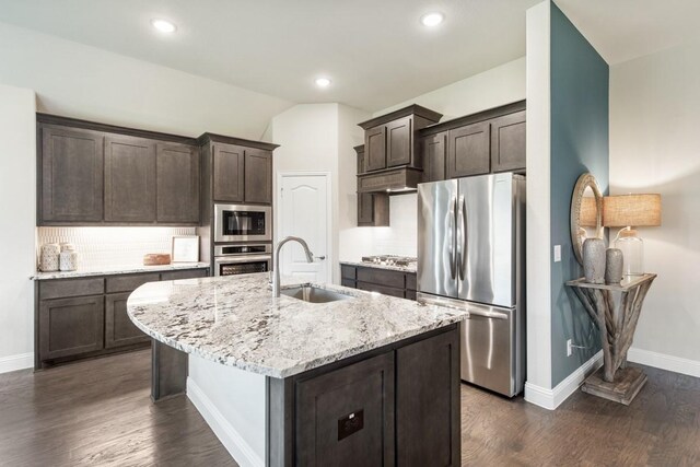 kitchen featuring stainless steel appliances, an island with sink, sink, and dark brown cabinetry