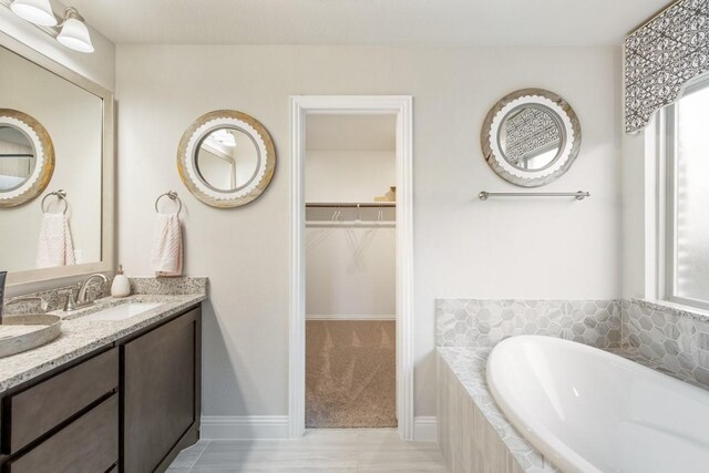 bathroom with vanity and tiled bath