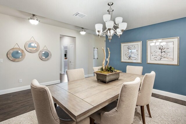 dining area featuring dark wood-type flooring and an inviting chandelier