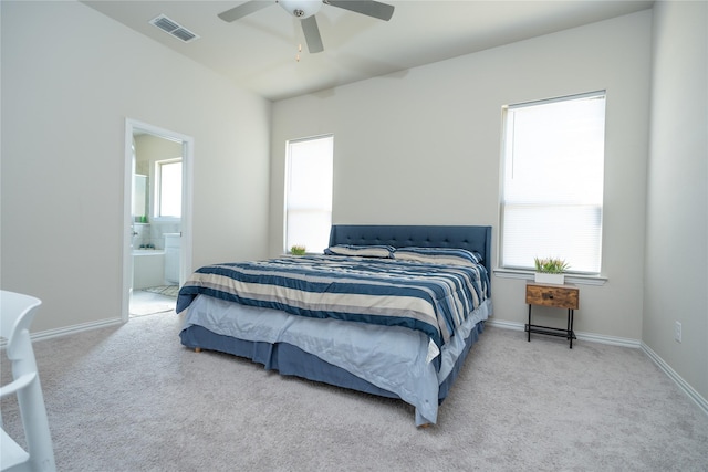 carpeted bedroom with multiple windows, connected bathroom, and ceiling fan