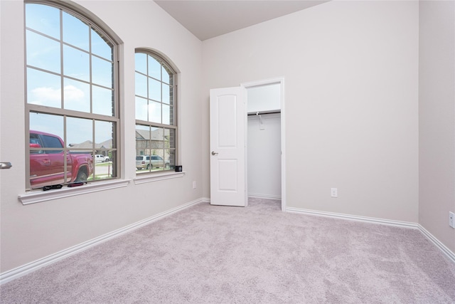 unfurnished bedroom featuring light colored carpet, a spacious closet, and a closet