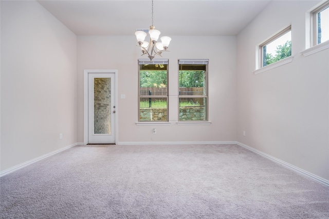 empty room with a notable chandelier and carpet flooring