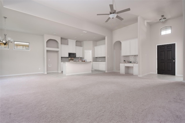 unfurnished living room with a high ceiling and ceiling fan with notable chandelier