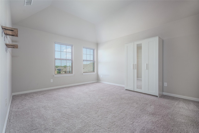 unfurnished bedroom featuring lofted ceiling and light carpet