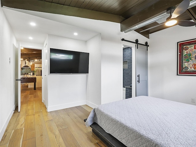 bedroom with wood ceiling, lofted ceiling with beams, ceiling fan, a barn door, and light hardwood / wood-style floors