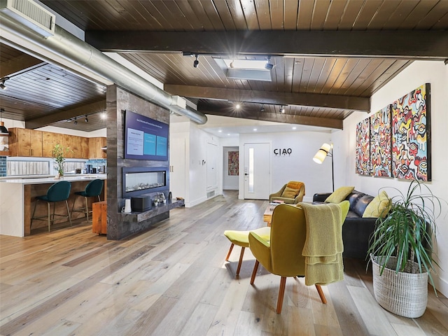 living room featuring wood ceiling, rail lighting, beam ceiling, and light wood-type flooring