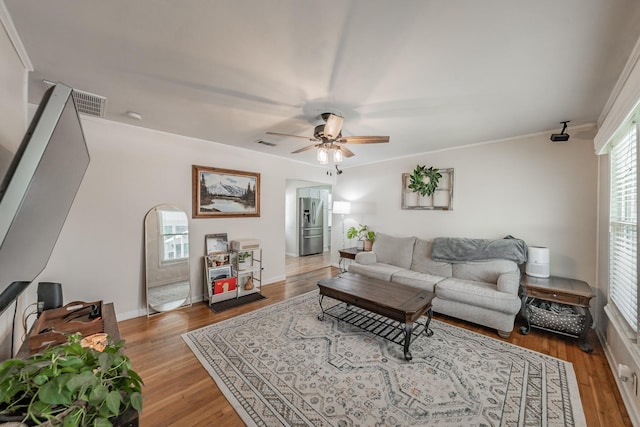 living room with plenty of natural light, light hardwood / wood-style floors, ornamental molding, and ceiling fan