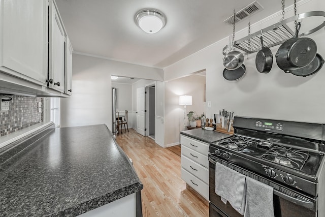 kitchen featuring white cabinets, crown molding, light hardwood / wood-style flooring, and black range with gas cooktop