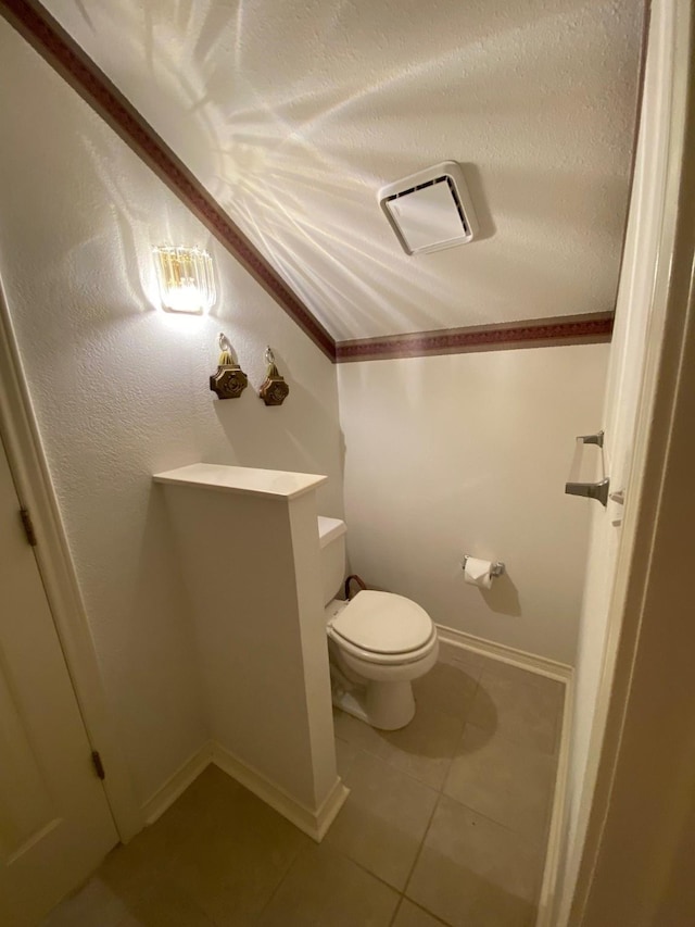 half bathroom with tile patterned flooring, toilet, baseboards, a textured ceiling, and visible vents