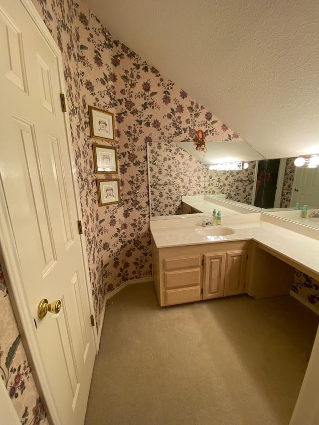 bathroom featuring wallpapered walls, vanity, baseboards, and a textured ceiling
