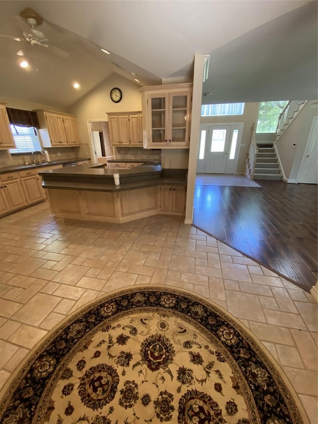 kitchen featuring lofted ceiling, dark countertops, ceiling fan, a peninsula, and glass insert cabinets
