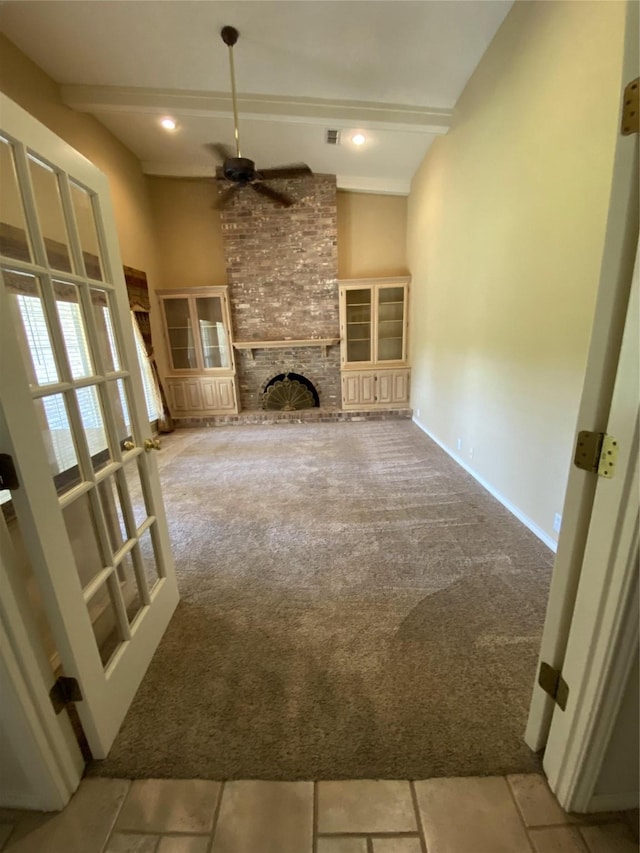 unfurnished living room with carpet, baseboards, beamed ceiling, a ceiling fan, and a fireplace