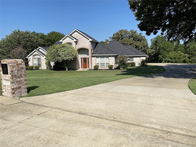 view of front of home featuring a front lawn, brick siding, and concrete driveway